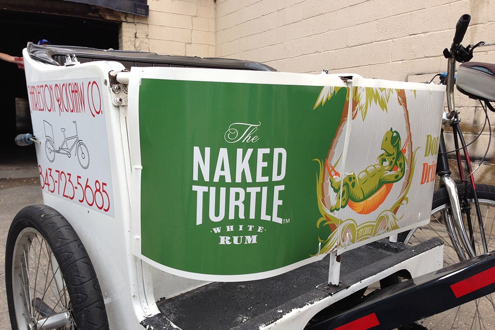 Naked Turtle Rum ad on the front gate of Charleston Rickshaw bike